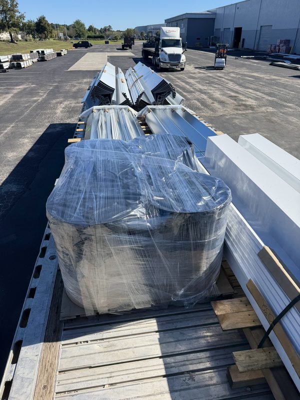 Flatbed with wrapped and banded roofing metal bundles on dunnage